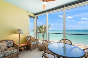 Ein Zimmer mit Korbmöbeln, einem Glastisch und Blick auf das Meer.