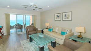 A living room with a sofa, chairs, a coffee table, and a view of the ocean through large windows. - Endless Gulf Views, Endless Relaxation (Siesta Key)