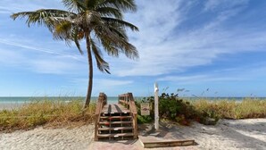 A wooden staircase leading to a beach with a palm tree and a signpost. - Endless Gulf Views, Endless Relaxation (Siesta Key)
