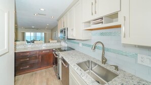 A modern kitchen with white cabinets, granite countertops, and stainless steel appliances. - Endless Gulf Views, Endless Relaxation (Siesta Key)