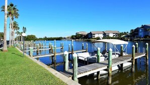 A marina with docked boats, a grassy area, and houses in the background. - Gulf Front, 3rd Floor, 1 bdr - A307, Gorgeous View! (Siesta Key)