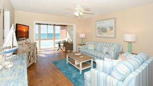 A living room with a sofa, coffee table, and a television. There is a view of the ocean through a large window. - Gulf Front, 3rd Floor, 1 bdr - A307, Gorgeous View! (Siesta Key)