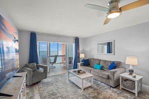 A modern living room with a sofa, armchair, coffee table, and a ceiling fan. - Escape to the Gulf – Prime Beachfront Location (Siesta Key)
