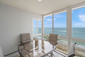 A room with a glass table and two chairs, large windows with a view of the ocean. - Escape to the Gulf – Prime Beachfront Location (Siesta Key)