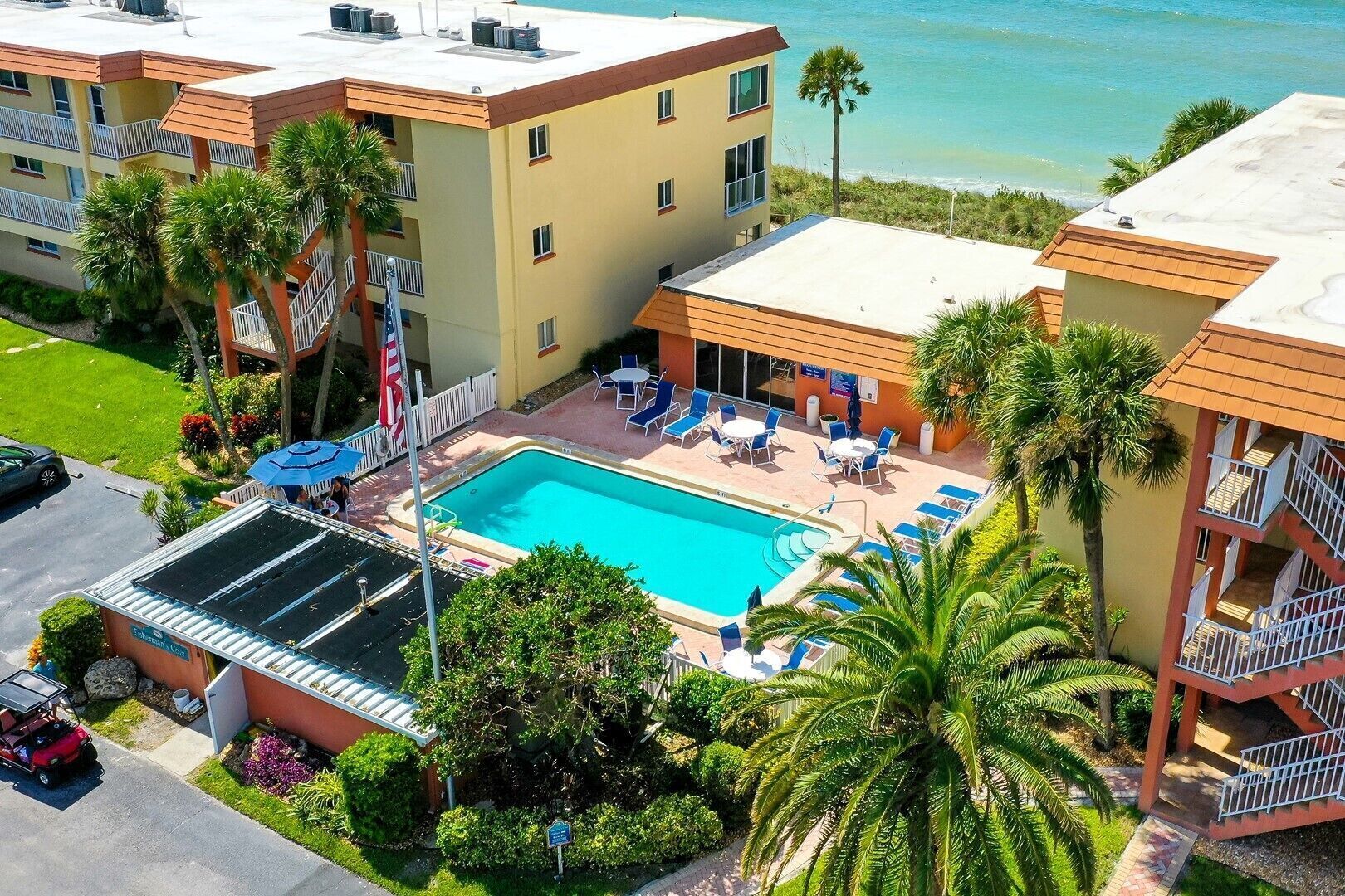 A hotel with a swimming pool, outdoor seating, and a view of the ocean.