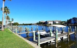 A marina with docked boats, a grassy area, and houses in the background. - Gulf-Front Condo – Perfect Siesta Key Stay (Siesta Key)