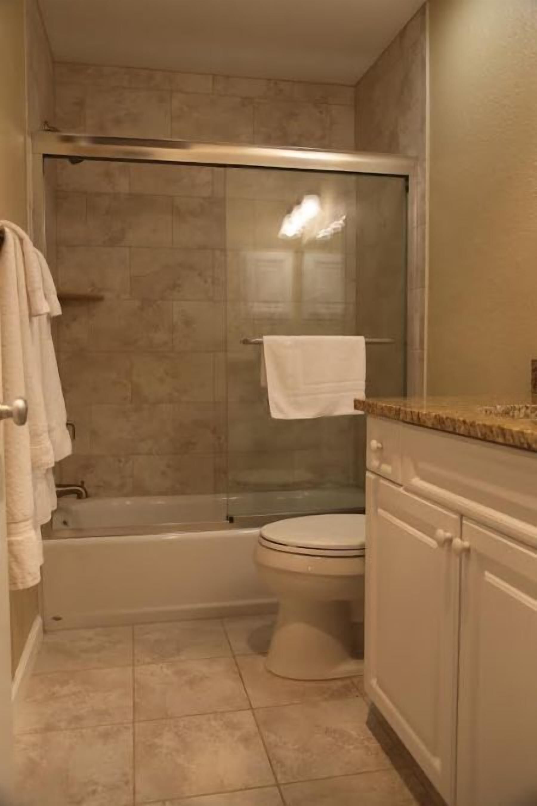A bathroom with a glass-enclosed shower, a toilet, and a vanity with drawers.