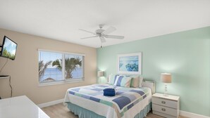 A bedroom with a bed, a ceiling fan, a TV, a window with blinds, and a nightstand with a lamp. - Watch the Sunset from Your Gulf-Front Balcony (Siesta Key)