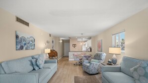 A living room with a sofa, armchairs, a coffee table, and a dining area with a table and chairs. - Watch the Sunset from Your Gulf-Front Balcony (Siesta Key)