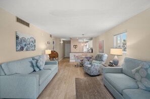 A living room with a sofa, armchairs, a coffee table, and a dining area with a table and chairs. - Watch the Sunset from Your Gulf-Front Balcony (Siesta Key)