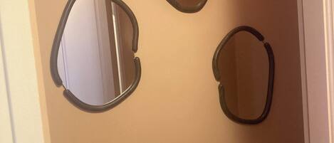 A bathroom with three oval mirrors on the wall, a white sink, and a toilet.
