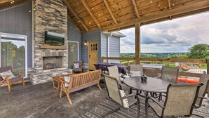 A covered patio with stone walls, a fireplace, outdoor furniture, and a view of the landscape. - Pool | Hot Tub | Pickleball | Firepit (Williamstown)