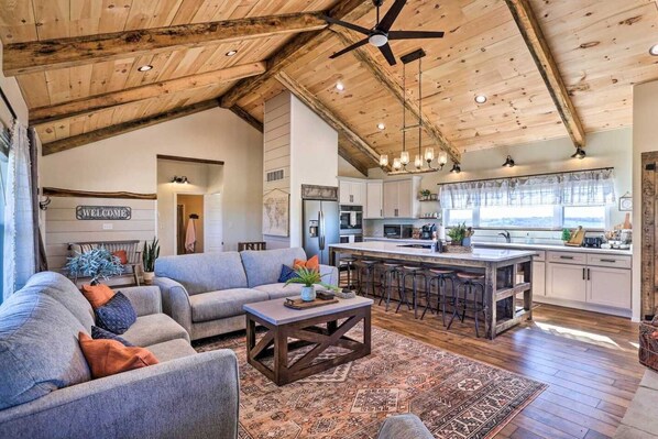 A spacious living area with a sofa, coffee table, and a kitchen with a bar and stools.