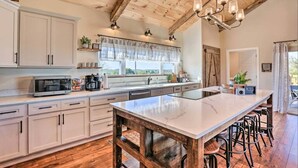 A kitchen with a large island, wooden ceiling beams, and a view of the outdoors. - Pool | Hot Tub | Pickleball | Firepit (Williamstown)