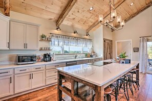 A kitchen with a large island, wooden ceiling beams, and a view of the outdoors. - Pool | Hot Tub | Pickleball | Firepit (Williamstown)