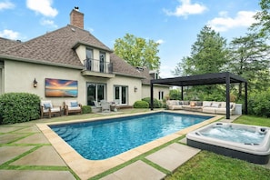 A residential property with a swimming pool, outdoor seating area, and a hot tub.