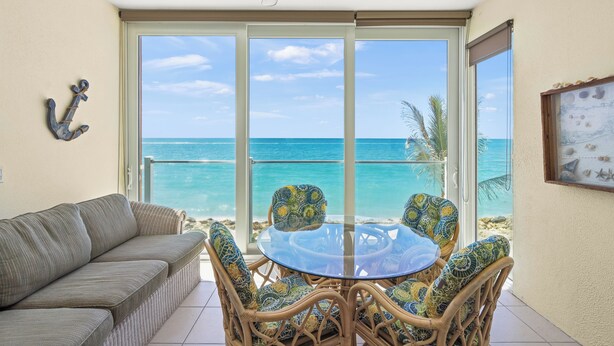 A balcony with a view of the ocean, a glass table, wicker chairs, and a sofa. - Sun, Sand & Gulf-Front Views (Sarasota)