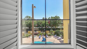 A window with a view of a pool area, including lounge chairs and a flagpole. - Orlando Comfort Close to Top Universal's Attractions (Orlando)