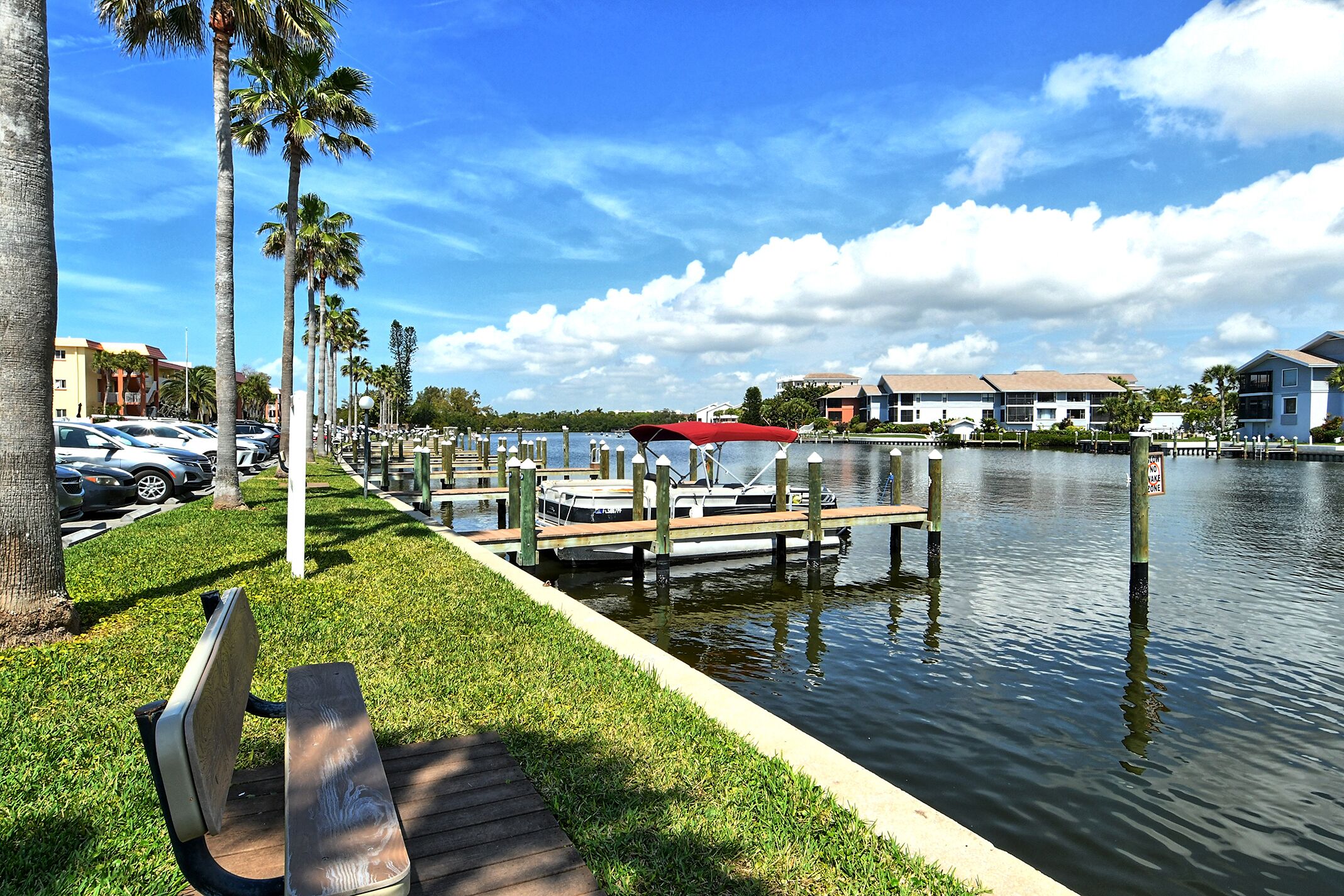 A waterfront dock with a boat, a bench, and a grassy area.