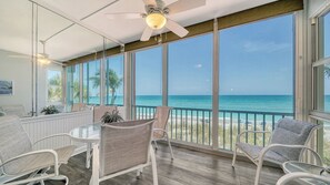 Ein Zimmer mit einem gläsernen Balkon, Deckenventilator und Meerblick.