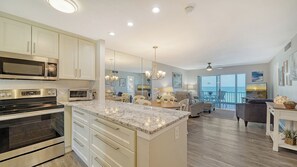 Eine moderne Küche mit integrierten Geräten, ein Essbereich mit Blick und ein Wohnzimmer mit Balkon.