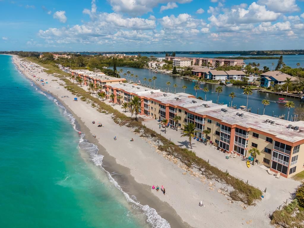 Un hôtel situé sur la côte, avec vue sur la plage, composé de plusieurs bâtiments et doté d’un port de plaisance.