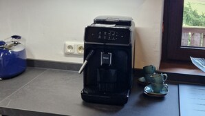 Una cuina amb una cafetera, un búllet blau i una finestra que ofereix vistes a l'exterior.