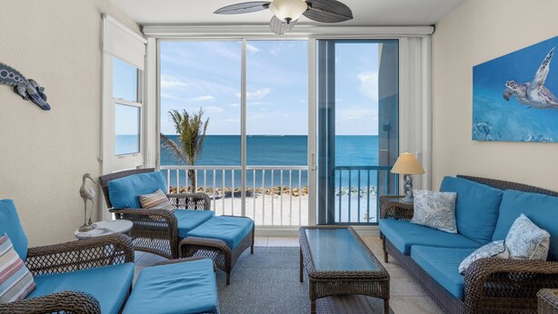 Ein Balkon mit Korbmöbeln, einem Deckenventilator und Blick auf den Strand.