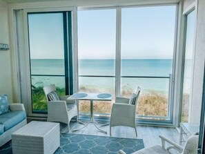 A balcony with a view of the ocean, furnished with a table and chairs, and a sofa. - The Ultimate Gulf-Front Getaway (Sarasota)