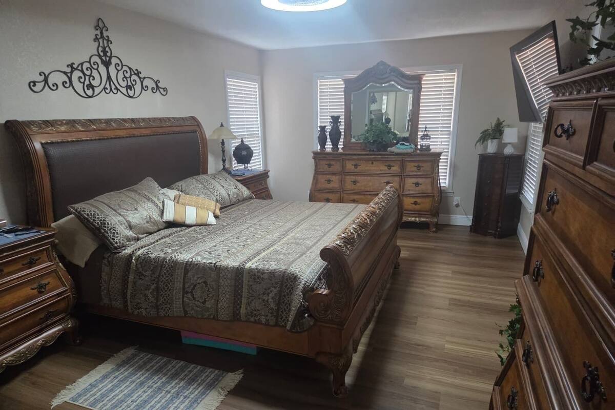 Une chambre à coucher avec un grand lit, une commode en bois et un miroir.