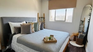 Ein Schlafzimmer mit Bett, Fenster mit Blick, Nachttisch und Spiegel.