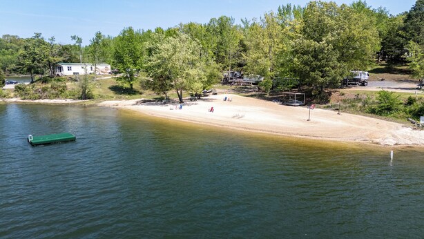 A lakeside area with a boat dock, a sandy beach, and trees. - Peaceful Cabin in New Concord, KY on Kentucky Lake at Missing Hill Resort (New Concord)