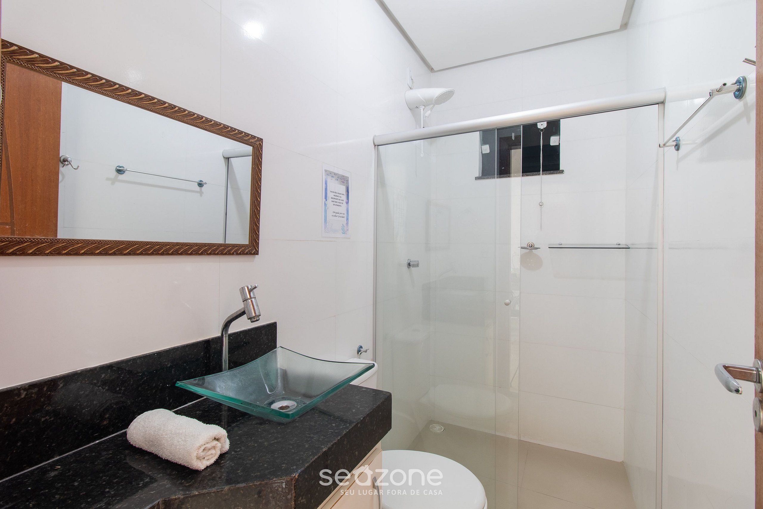 A modern bathroom with a glass sink, a large mirror, and a walk-in shower.