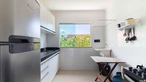 A compact kitchen with a window, white cabinets, a sink, and a stove. - Apts in Condominium w/ Pool and Barbecue - Ctys (Porto Seguro)