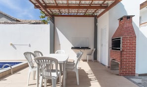 An outdoor patio with a table and chairs, a barbecue grill, and a swimming pool. - Apts in Condominium w/ Pool and Barbecue - Ctys (Porto Seguro)