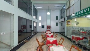 A spacious indoor area with multiple tables and chairs, a glass partition, and a sign indicating self-service options. - Apto Para 3 Pessoas na Rua Teresa (Petrópolis)