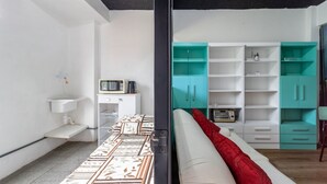 A modern bedroom with a bed, a white bedside table, a red pillow, and a teal-colored wardrobe with multiple shelves. - Apto Para 3 Pessoas na Rua Teresa (Petrópolis)