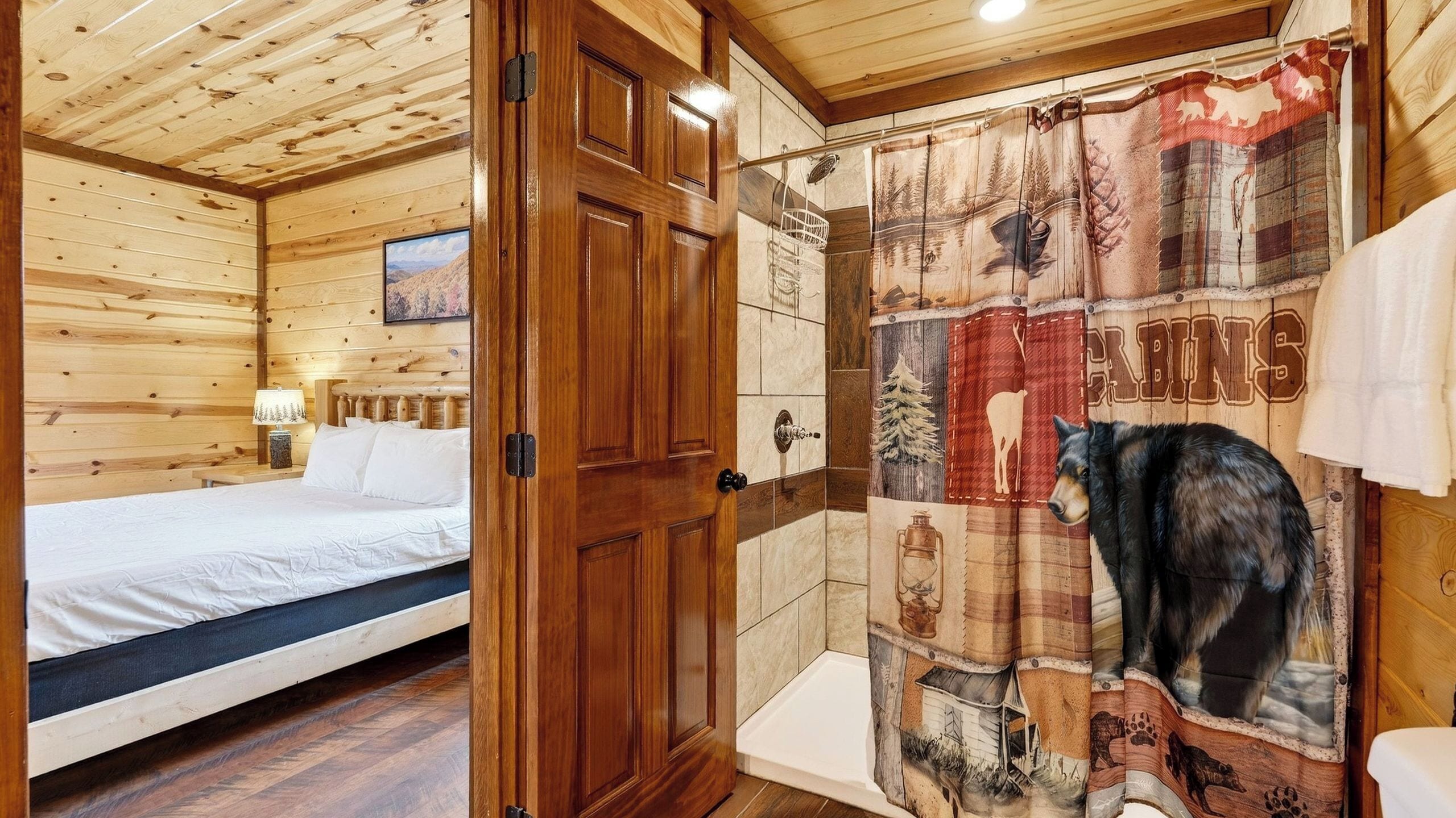 Ein Zimmer in einer Holzhütte mit einem Bett, einer Duschvorhang mit Tiermotiven und einer Holztür.
