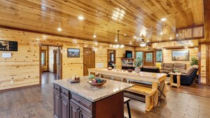 A spacious log cabin interior with a large wooden dining table, a kitchen area, and a cozy seating area. - Green Mountain Lodge by Avantstay Group Retreat Indoor Pool + Hot Tub + Game Room Pigeon Forge + Near Dollywood (Sevierville)