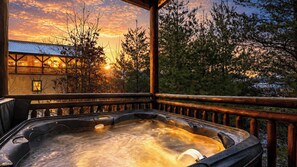 A hot tub with a wooden deck and railing, surrounded by trees and a building with a sloped roof. - Green Mountain Lodge by Avantstay Group Retreat Indoor Pool + Hot Tub + Game Room Pigeon Forge + Near Dollywood (Sevierville)