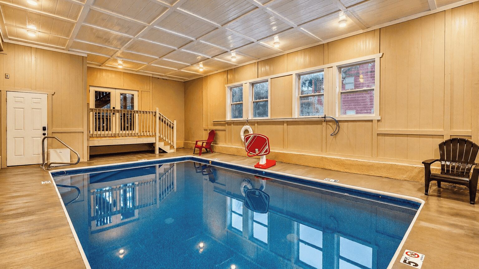 Una piscina interior con paredes de madera, una escalera y una silla.