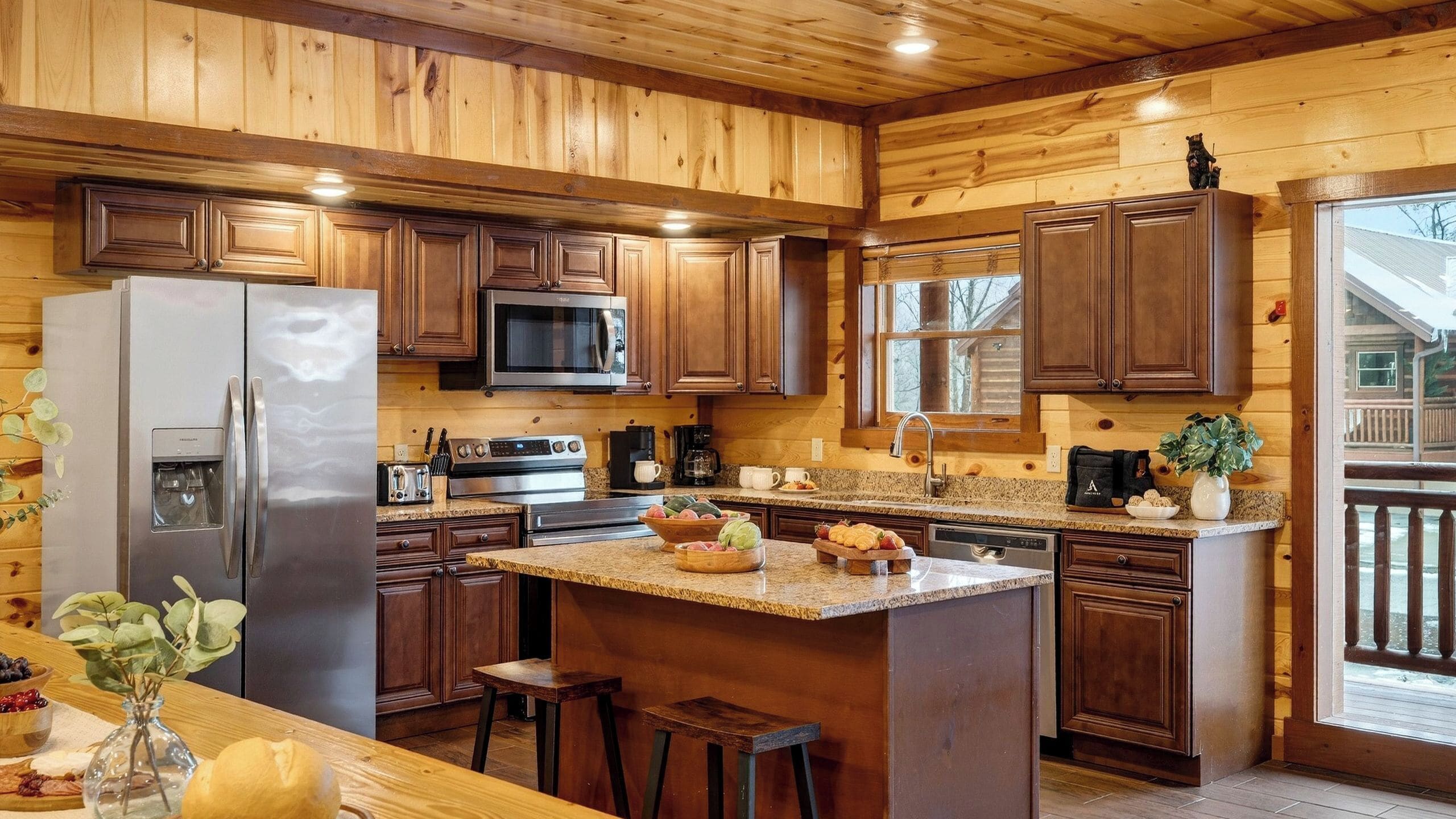 A kitchen with wooden cabinets, stainless steel appliances, granite countertops, and a large island with stools.