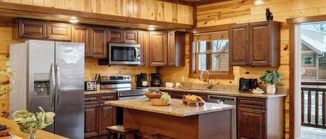 A kitchen with wooden cabinets, stainless steel appliances, granite countertops, and a large island with stools.