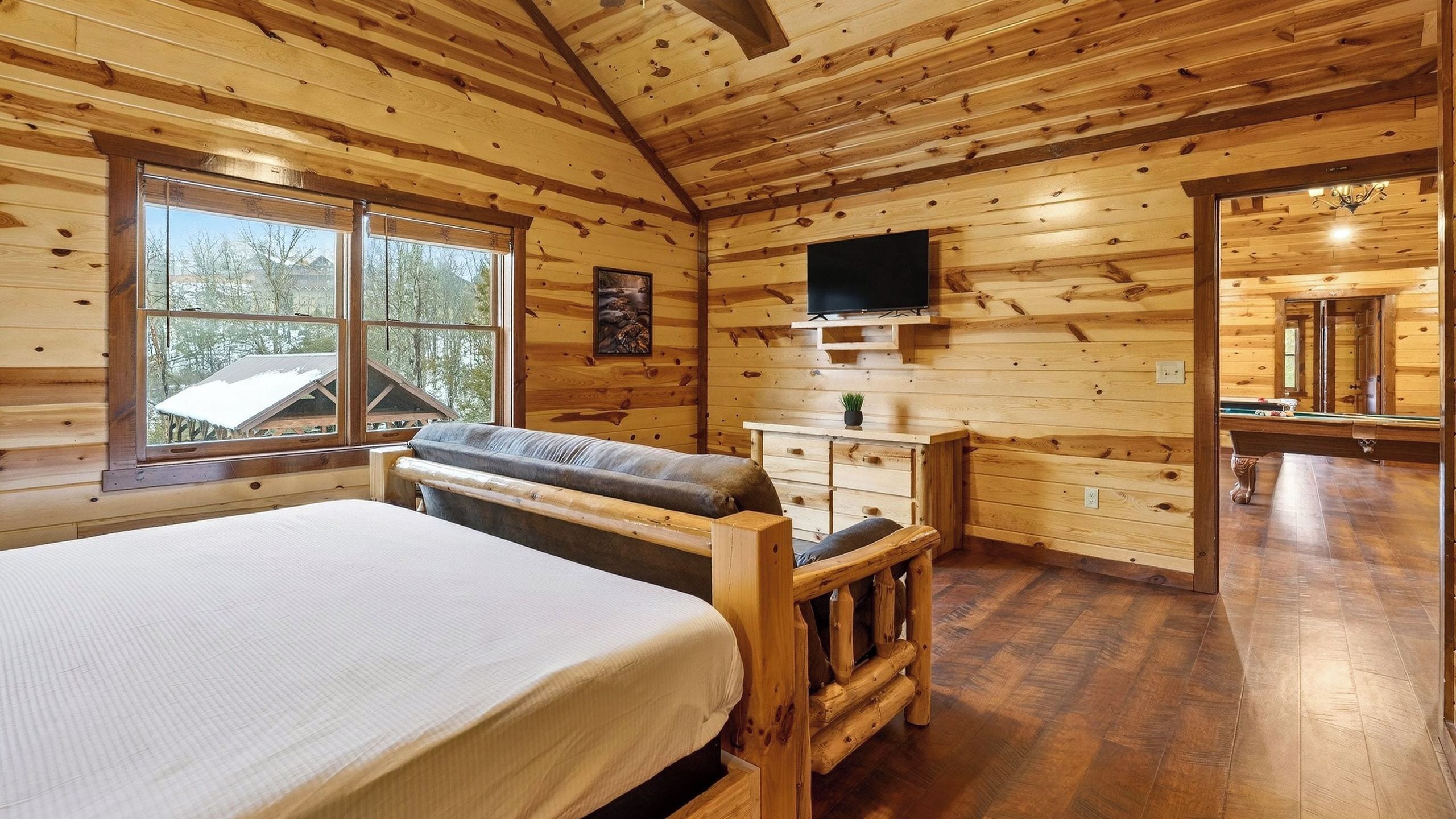 A wooden cabin with a bed, a television, and a pool table.