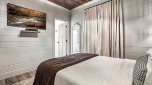 Une chambre à coucher avec un lit, un tableau, un miroir et une porte.