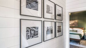 Une chambre avec un lit, une table de chevet et un mur décoré de photos encadrées.