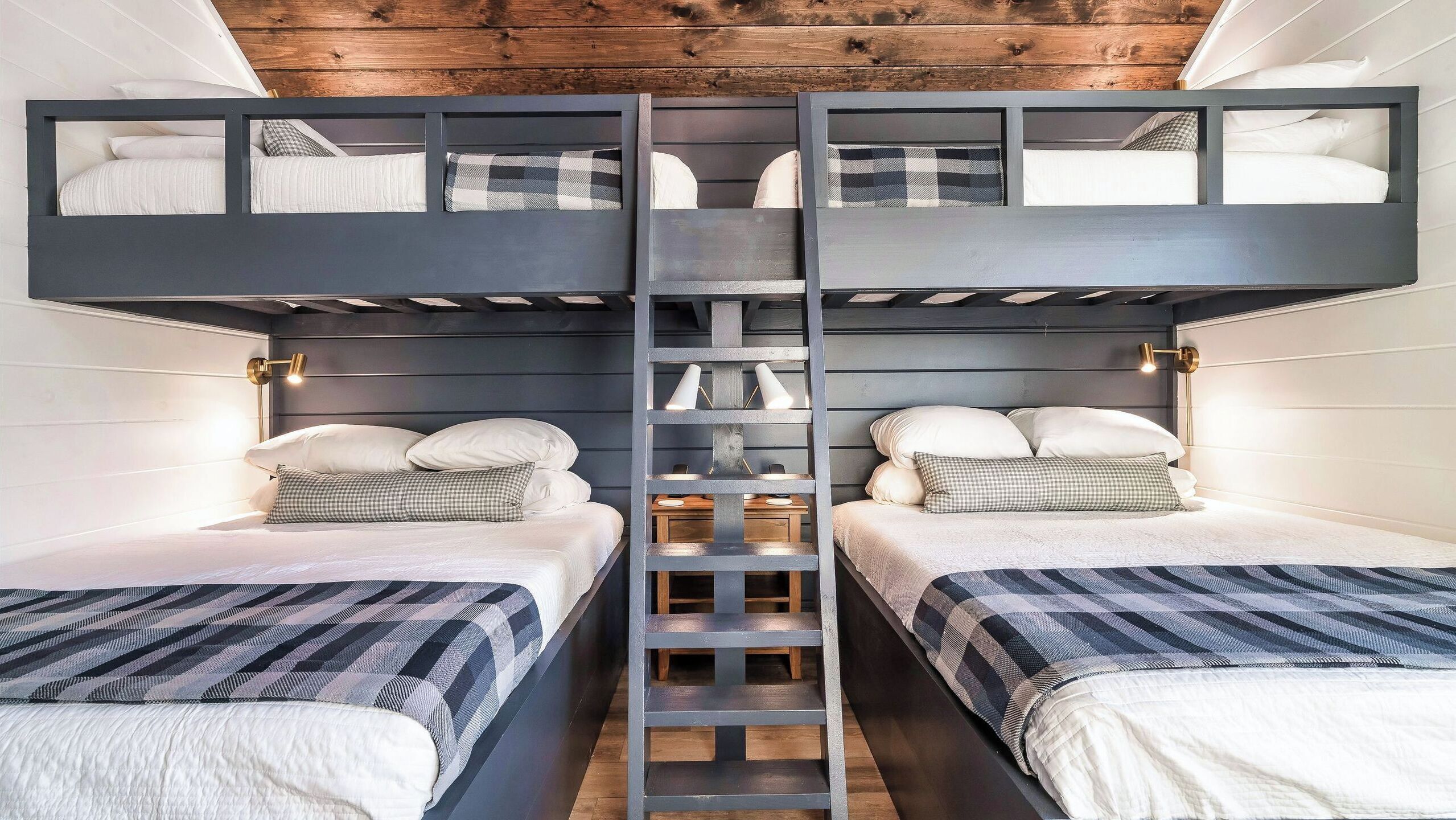 Habitación con literas, dos camas, una escalera y lámparas de noche.