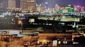 A nighttime cityscape with illuminated buildings and a waterfront.