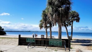 Ein Strand mit Palmen, einem Schild, das Alkoholkonsum verbietet, und einem Parkschild mit einer Zwei-Stunden-Zeitbegrenzung.