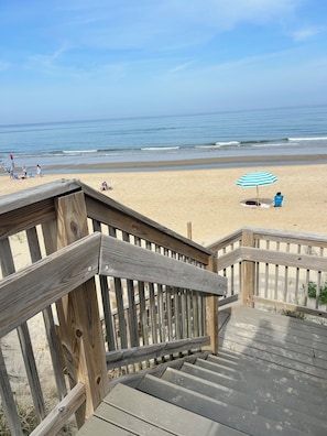 Un escalier en bois mène à une plage d’où l’on a une vue dégagée sur l’océan.